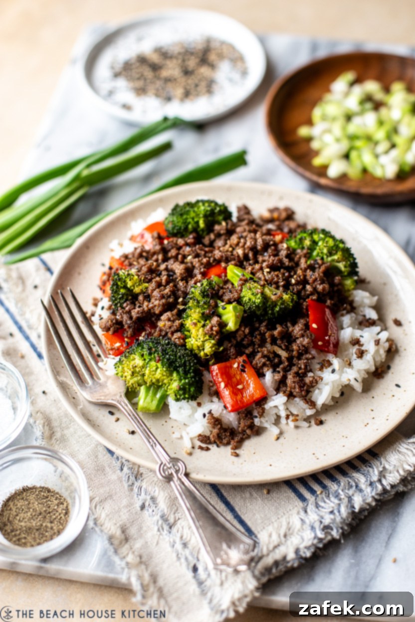 Up close photo of a plate of beef, broccoli and red peppers over rice