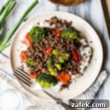Korean Beef with Broccoli and Peppers served on a cute light plate with a metal fork on the side