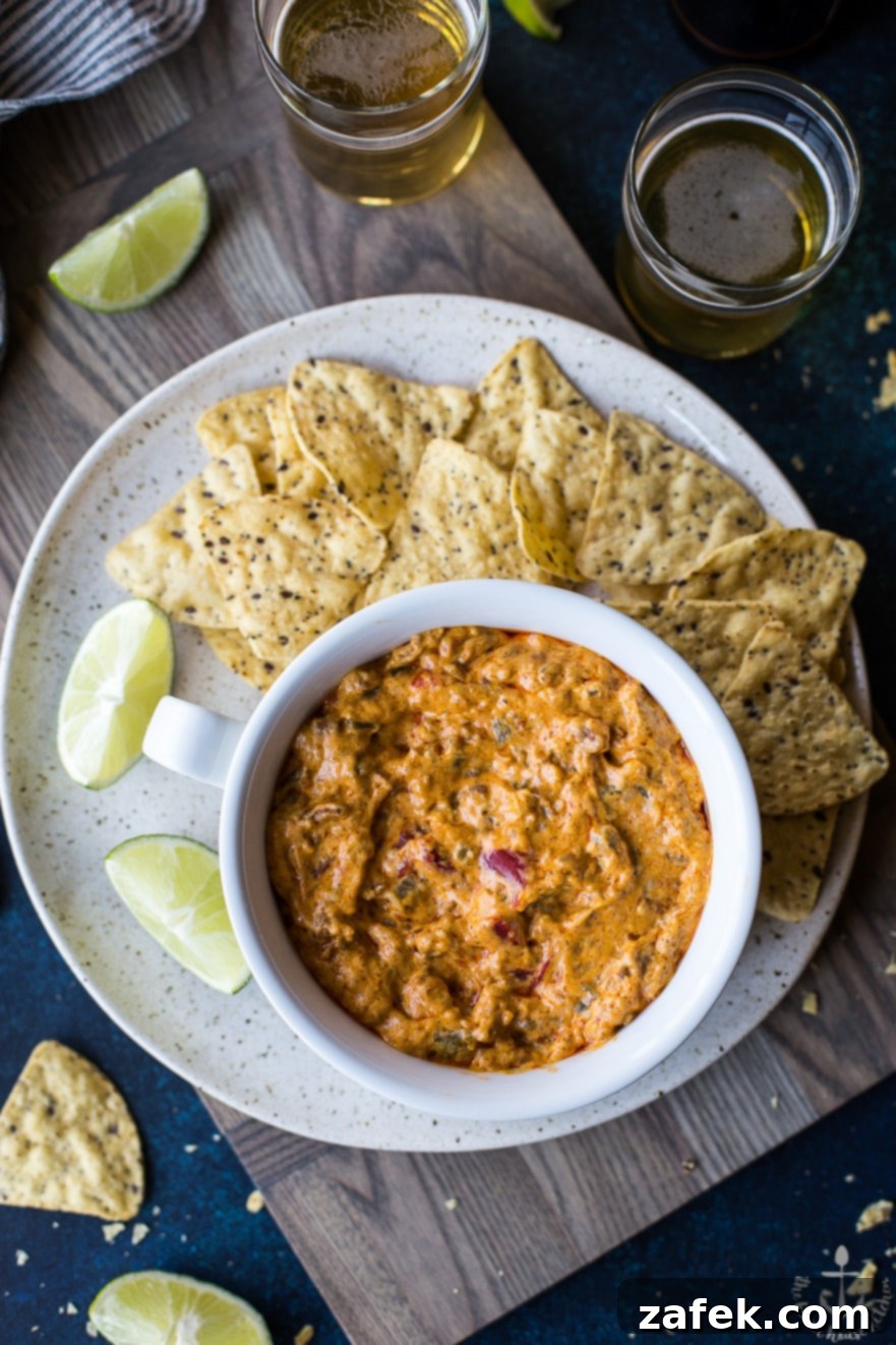 Cheesy Mexican Chorizo Dip A large bowl of hot, cheesy Mexican Chorizo Dip, served alongside a pile of golden, crunchy tortilla chips, ready for a party.