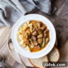 Overhead photo of Hungarian beef goulash in a white bowl on a wooden board