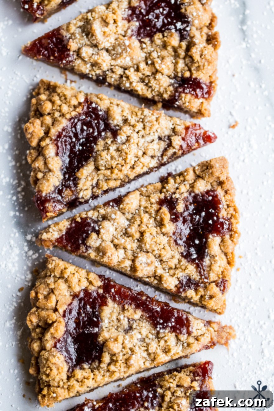 Wedges of jam crumb cookies in a row of six cookies on a light surface
