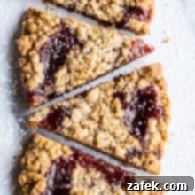 Wedges of jam crumb cookies in a row of six cookies on a light surface