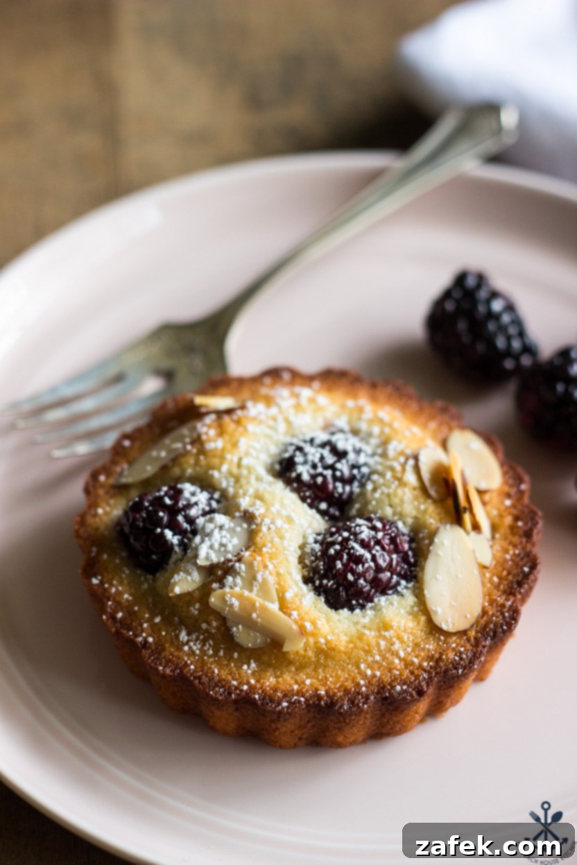 Elegant Blackberry Almond Bites 6 Up close photo of a financier topped with fresh blackberries and perfectly toasted sliced almonds