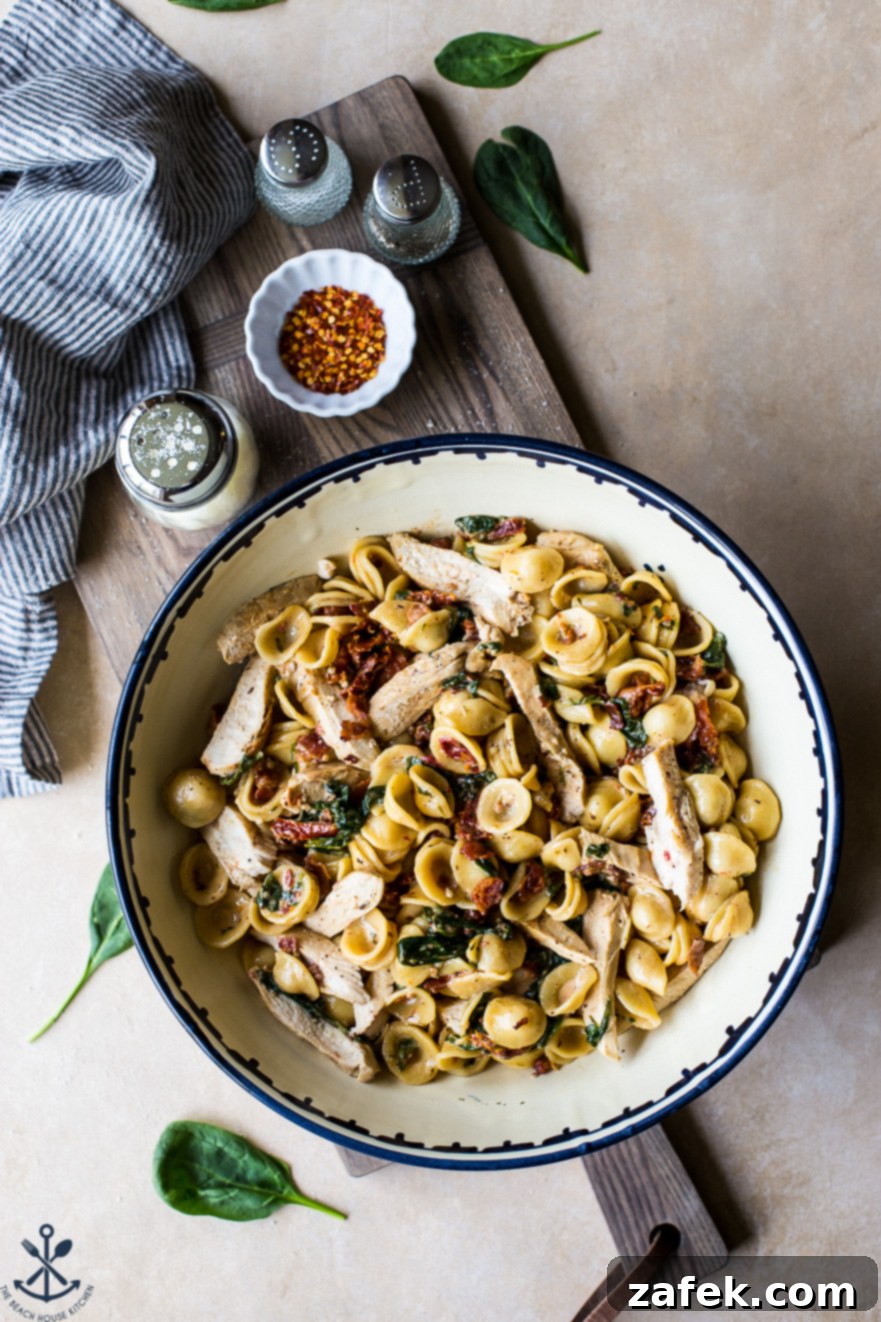 Tuscan Chicken Pasta with Sun-Dried Tomato Bacon Cream 2 Chicken Pasta with Sun-Dried Tomato Bacon Cream Sauce in a large bowl on a wooden board