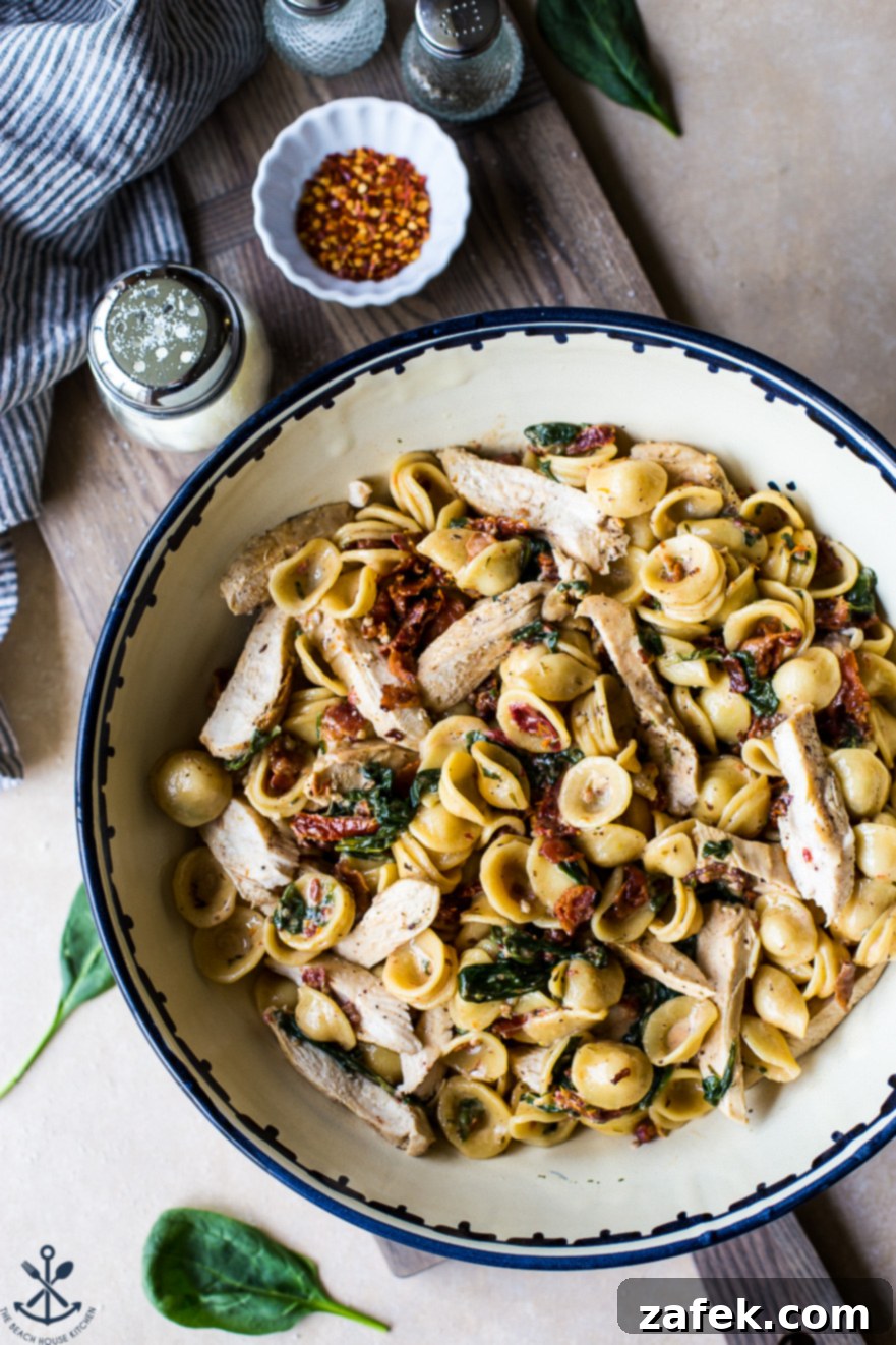 Tuscan Chicken Pasta with Sun-Dried Tomato Bacon Cream 4 Overhead photo of Chicken Pasta with Sun-Dried Tomato Bacon Cream Sauce in a bowl on a wooden board