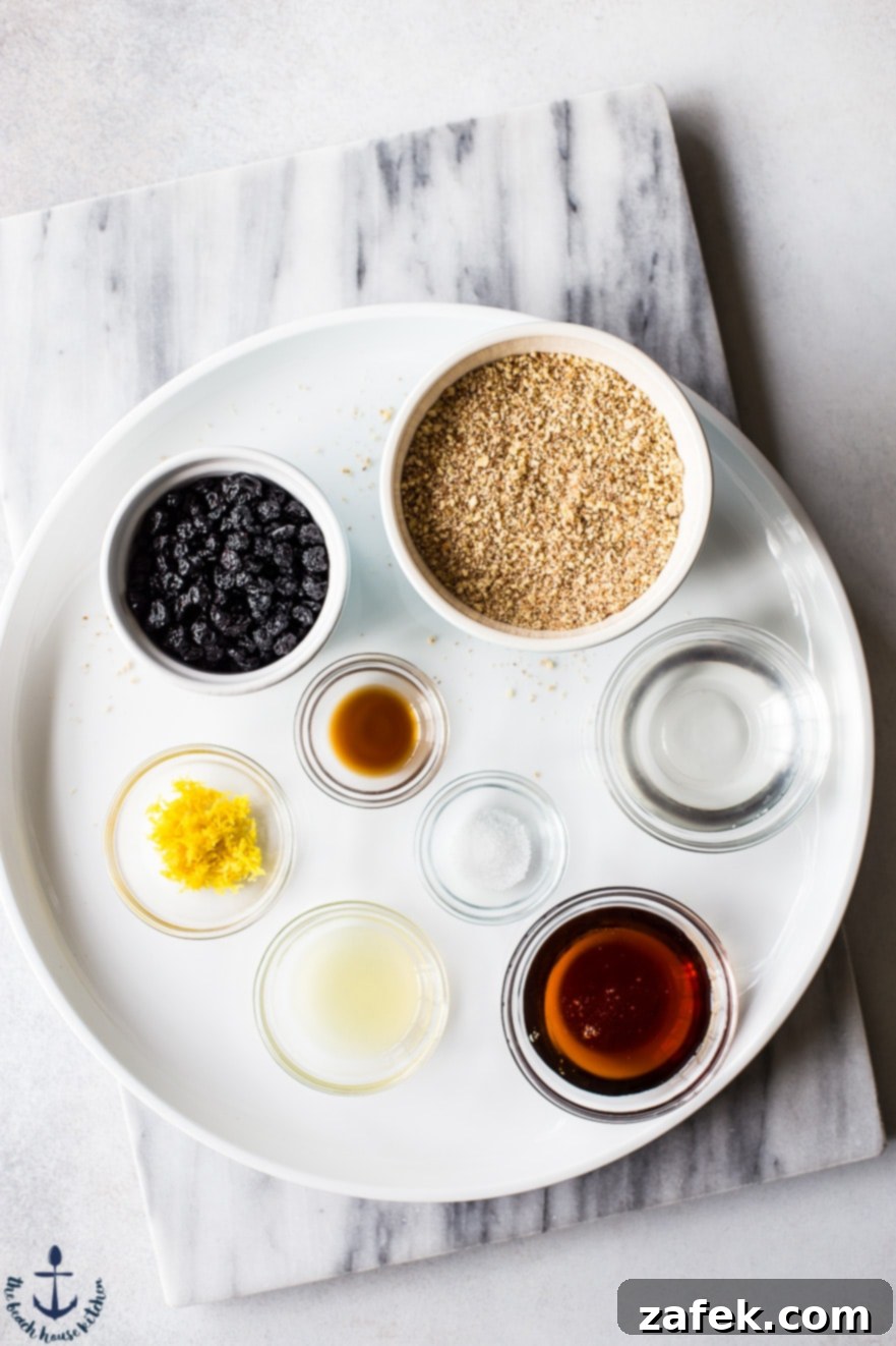 Flat lay photo showcasing all the fresh ingredients needed for blueberry lemon breakfast bites, including whole almonds, dried blueberries, lemons, and maple syrup.