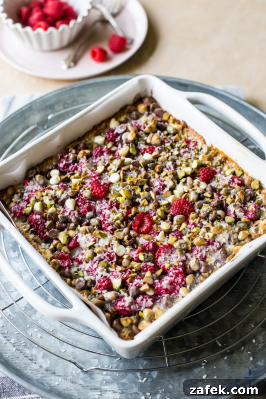 A baking pan filled with golden-brown Raspberry Pistachio Magic Bars, showcasing their inviting texture and beautiful topping distribution.