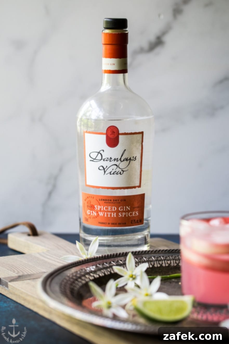 The components of the Spiced Rhubarb Collins on a silver tray, including the gin bottle, fresh rhubarb stalks, limes, and the prepared cocktail, ready to be enjoyed.