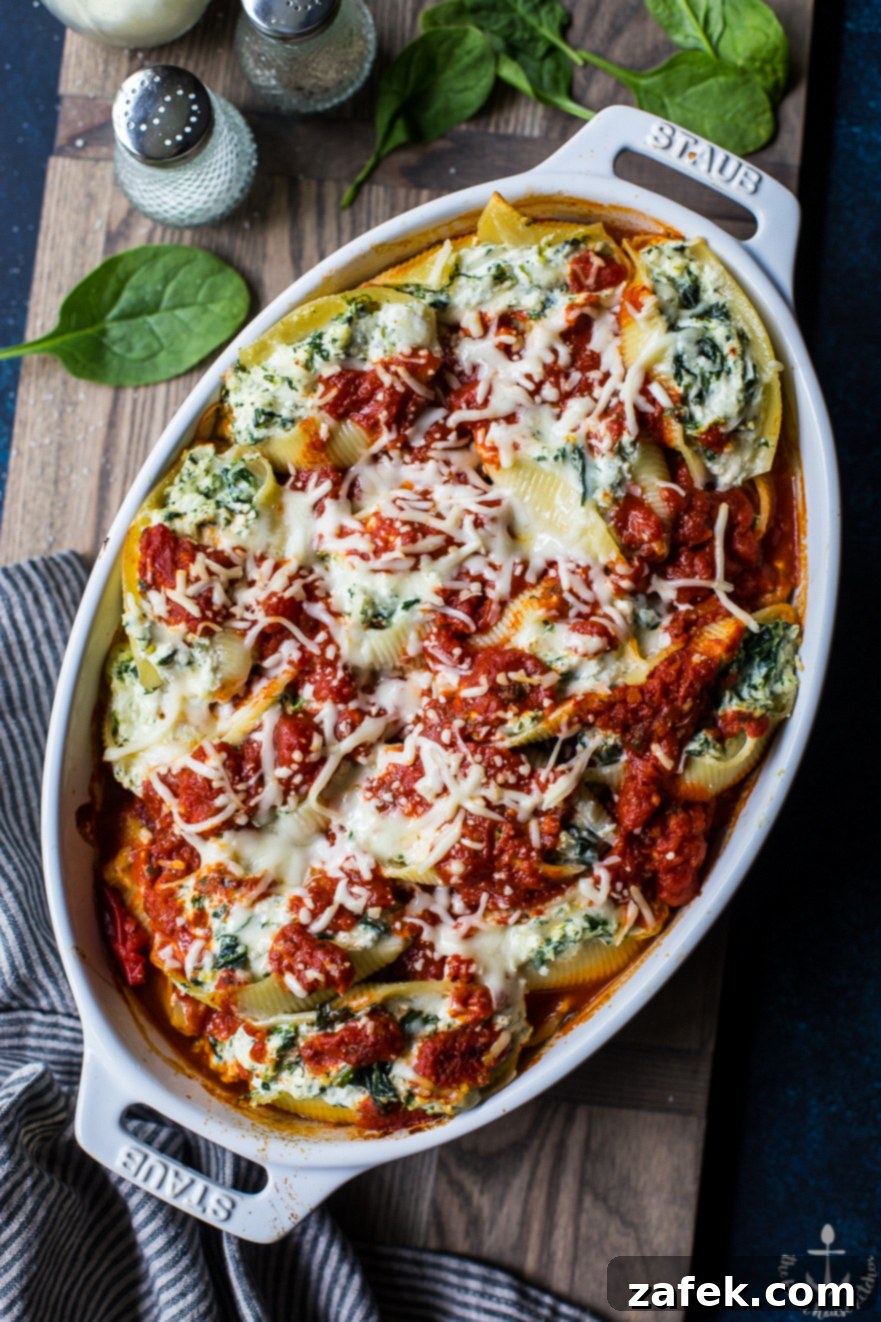 Close-up overhead photo of easy spinach stuffed shells in a white dish on a wooden board