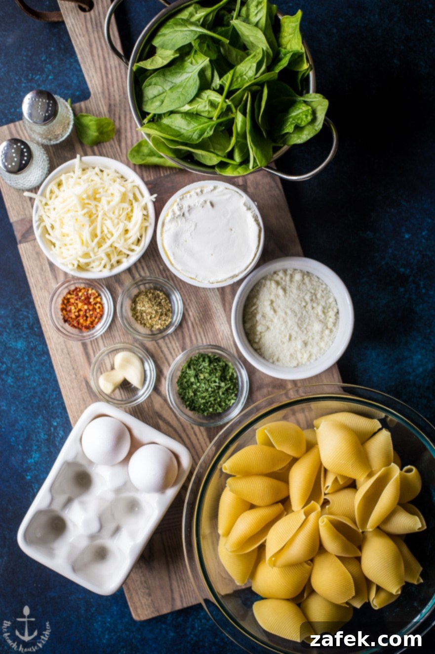 Overhead photo of ingredients for easy spinach stuffed shells in bowls on wooden board including pasta, cheeses, and spinach