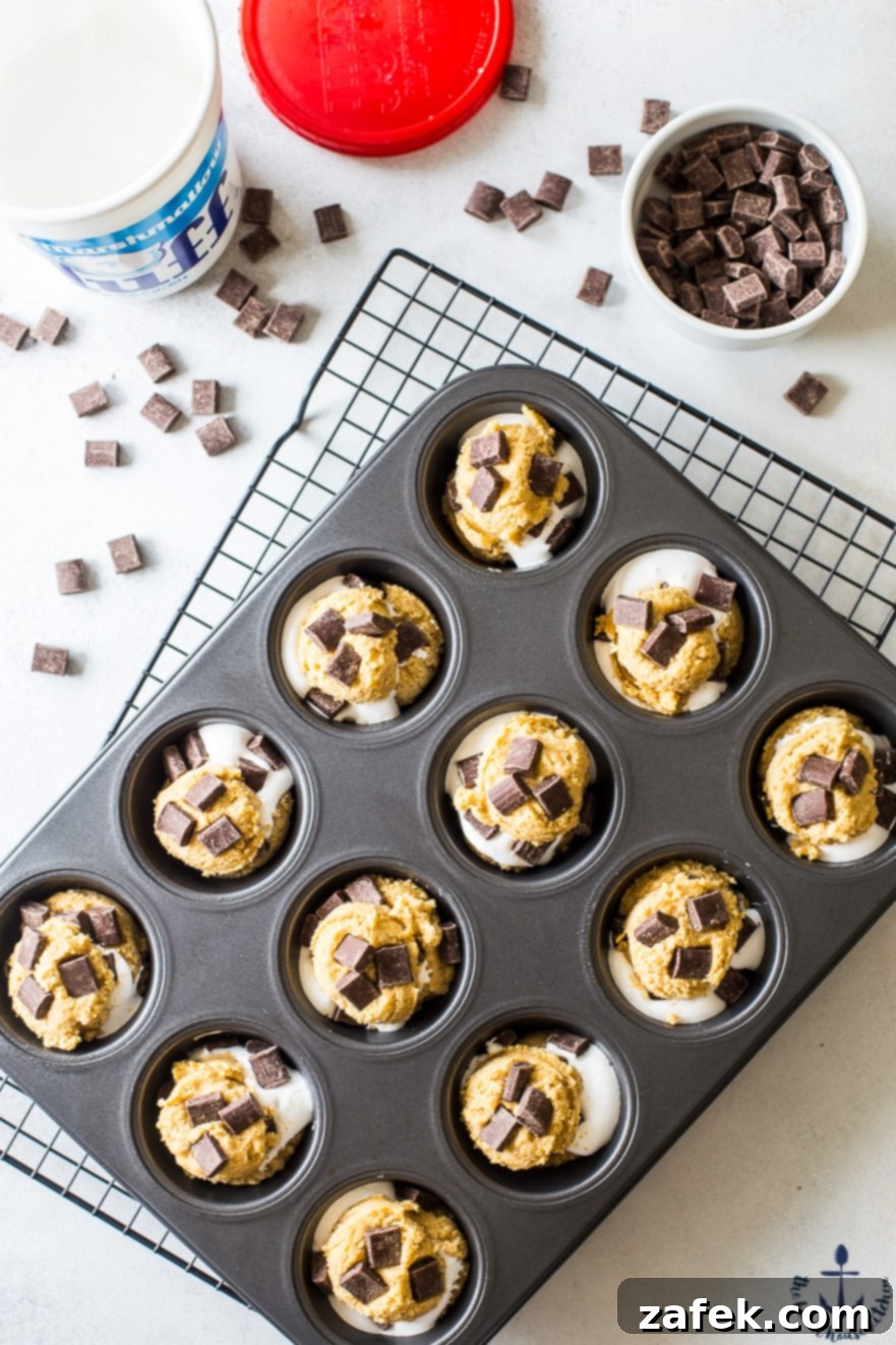 Close-up overhead photo of S'mores Cups batter in a muffin tin, showing chocolate chunks