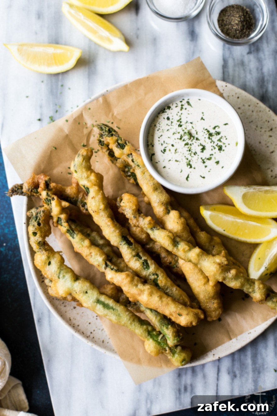 Overhead photo of asparagus tempura with horseradish cream sauce on a plate on a marble board