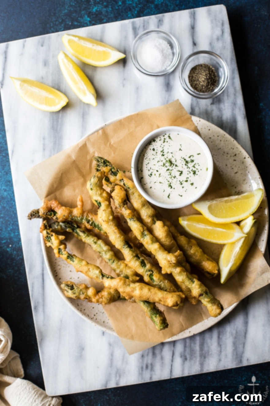 Overhead photo of asparagus tempura with horseradish cream sauce on a plate on a marble board