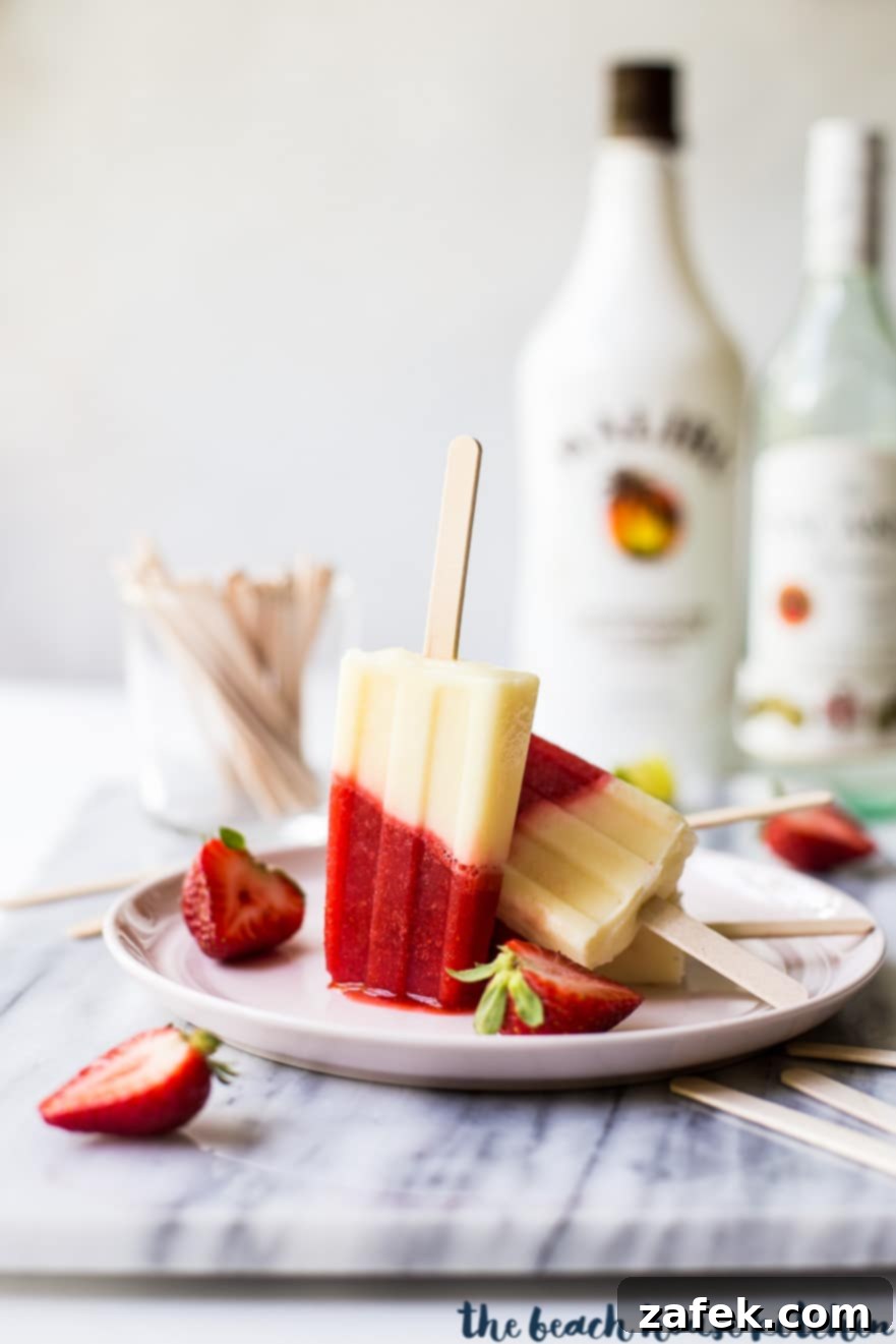 Miami Vice Boozy Popsicles on a pink plate surrounded by sliced strawberries