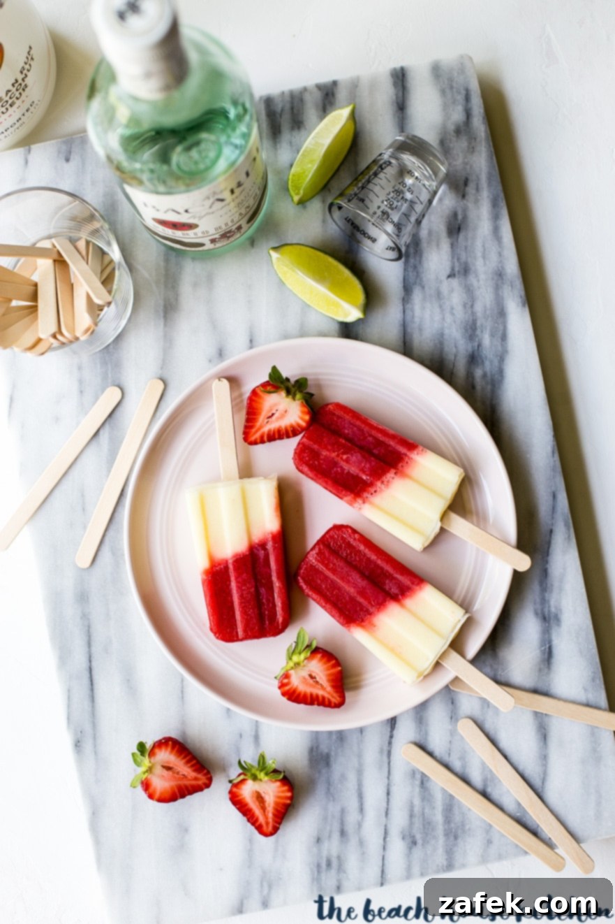 Overhead photo of Miami Vice boozy popsicles on pink plate with sliced strawberries