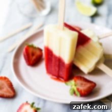 Miami Vice Boozy Popsicles on a pink plate surrounded by a few halved strawberries