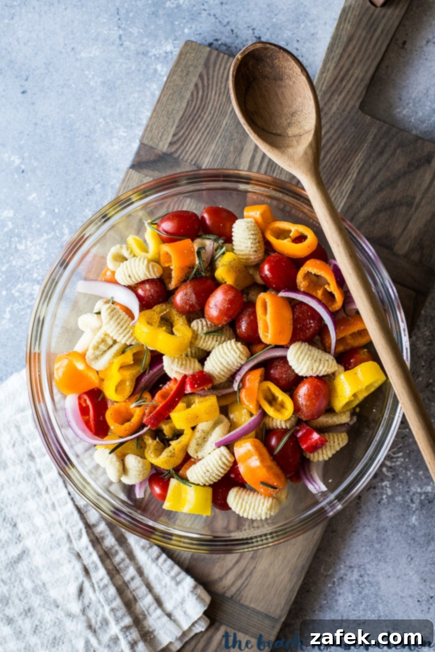 Golden Gnocchi and Veggies Sheet Pan Supper 4 Overhead photo of veggies and gnocchi in a clear bowl with a wooden spoon