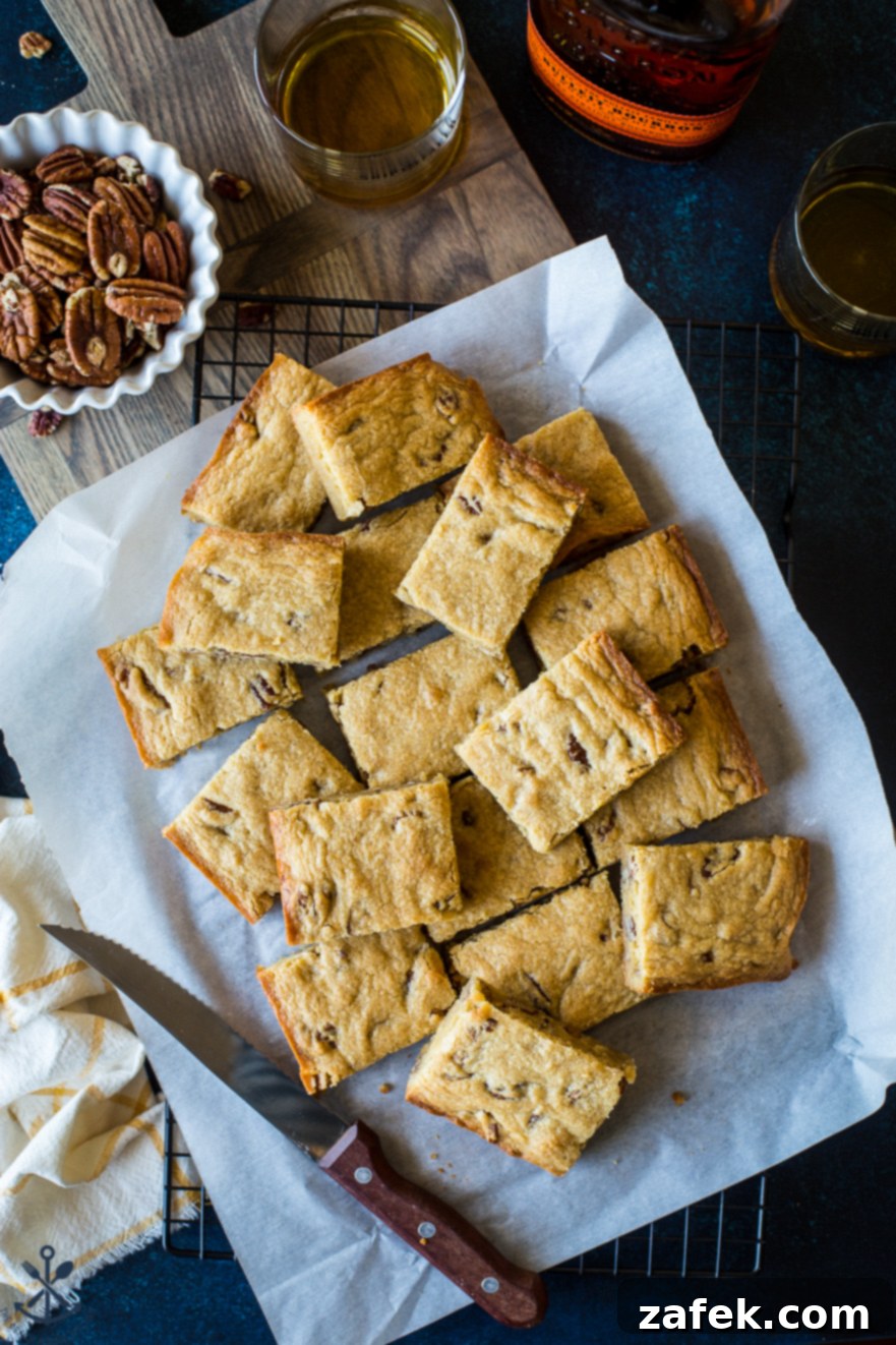 Overhead photo of perfectly sliced pecan bourbon blondies arranged on parchment paper, highlighting their moist interior and pecan pieces.