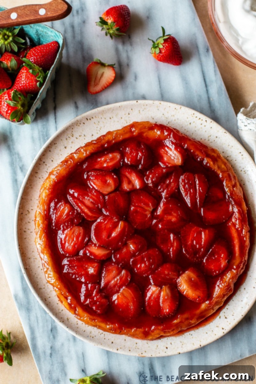 Blushing Strawberry Caramel Tart 4 Up close overhead photo of a strawberry tarte tatin, highlighting the perfectly browned pastry and vibrant, glistening strawberries.
