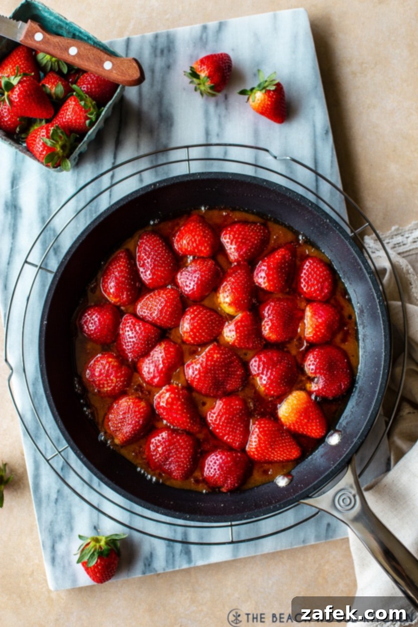 Blushing Strawberry Caramel Tart 5 Overhead photo of a cast iron skillet filled with bright red, sliced strawberries, ready for caramelization.