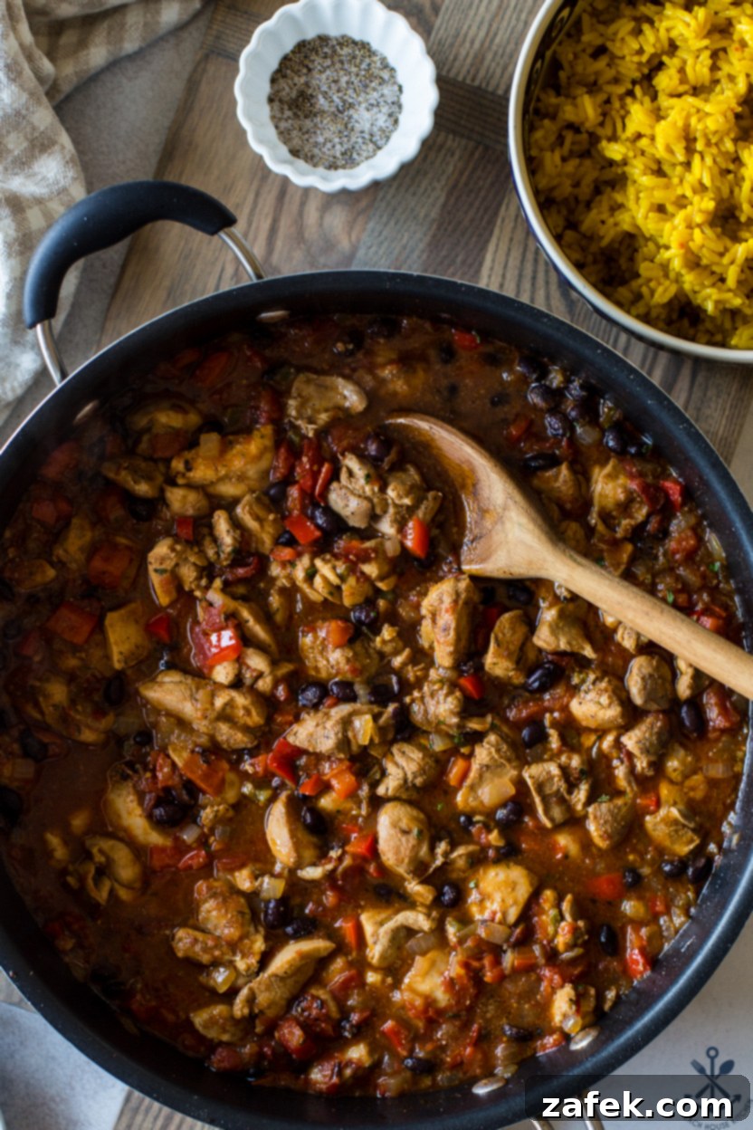 Up close overhead photo of a skillet showing chicken, rice, tomatoes, and black beans in detail