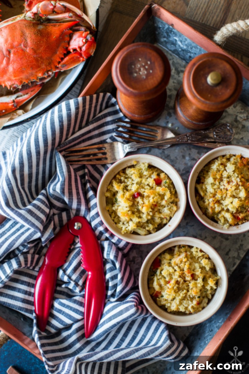 Fiery Crab Bake 2 Overhead photo of a tray of deviled crab in ramekins with a salt and pepper shaker and cooked crabs off to the side