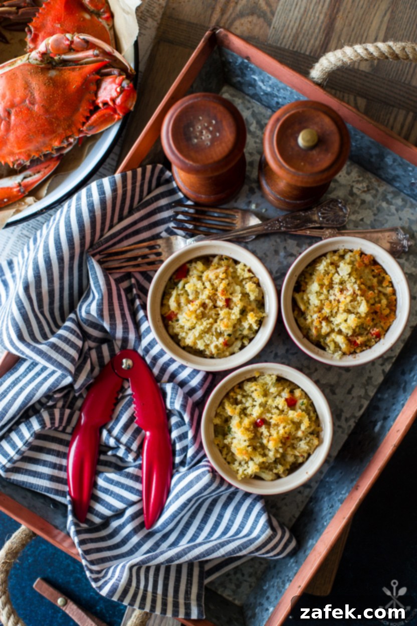 Fiery Crab Bake 6 Overhead photo of a tray of ramekins filled with deviled crab as well as wooden salt and pepper grinders and cooked crabs off to the side