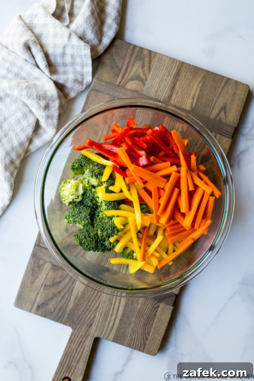 Spring Vegetable Pasta 3 Overhead photo of a glass bowl of sliced red, orange and yellow peppers and broccoli florets, ready for cooking