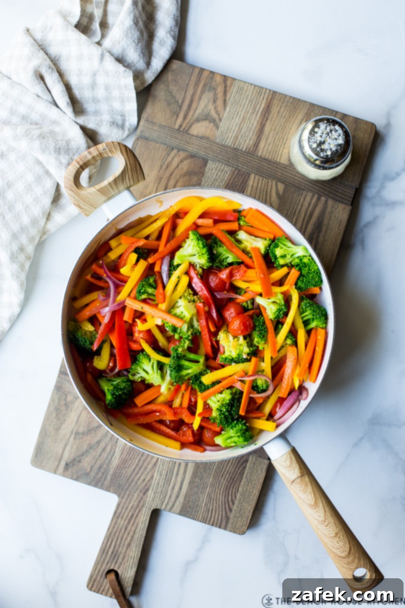 Spring Vegetable Pasta 5 Overhead photo of a skillet of cooked fresh veggies, including tomatoes, onions, and blanched vegetables