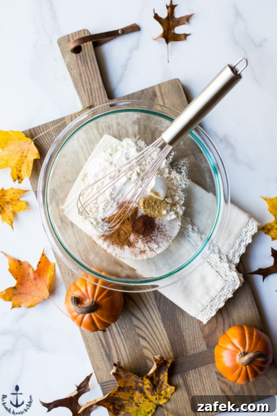 Overhead photo of ingredients for pumpkin fritters in a glass bowl on a wooden board