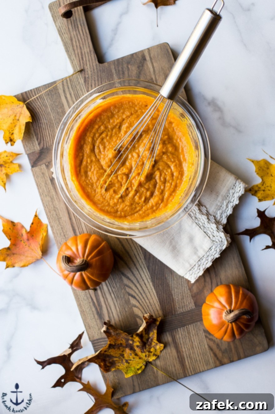 Overhead photo of batter in a bowl for pumpkin fritters in a bowl on a wooden board