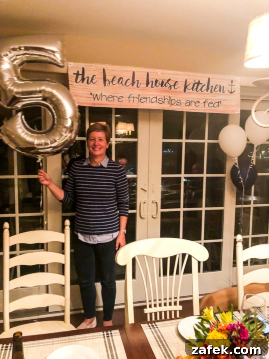 Armenian Honey Cake 5 Mary Ann from The Beach House Kitchen smiling, holding a large silver '5' balloon, celebrating the blog's fifth anniversary