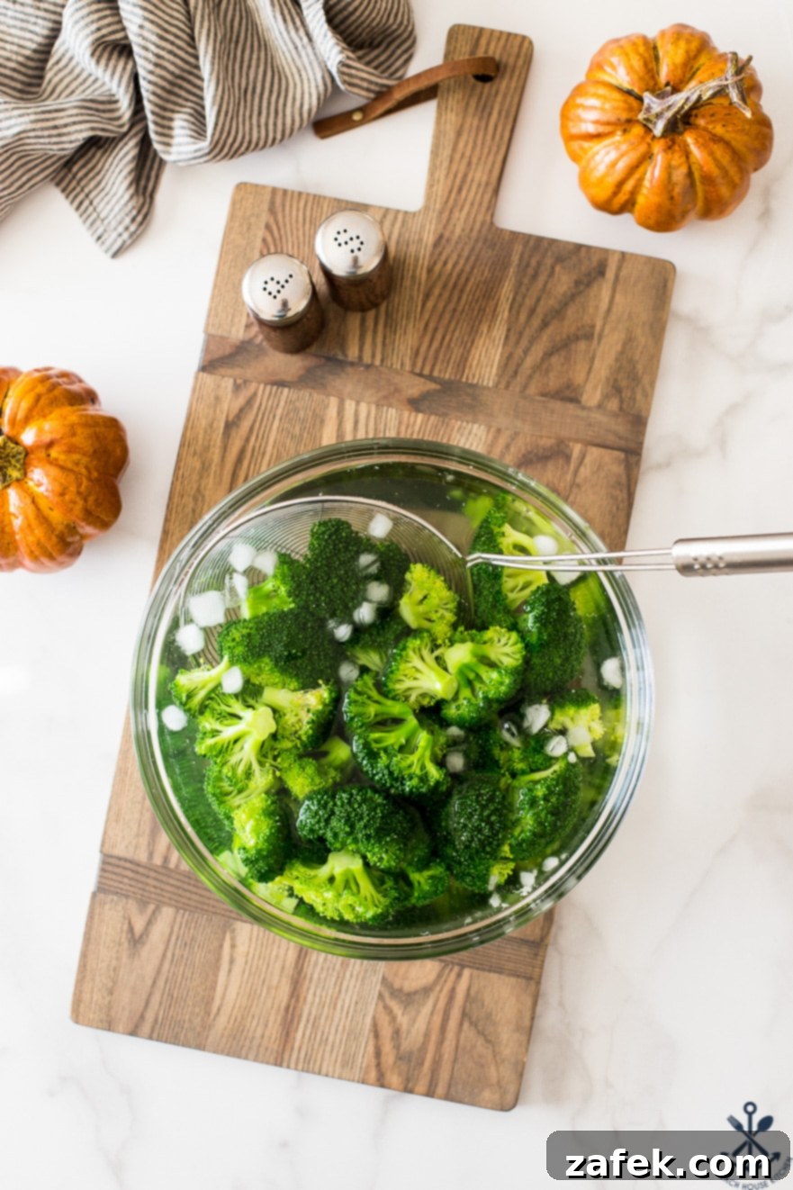 Effortless Festive Broccoli Bake 10 Overhead photo of bowl filled with broccoli, ice and water on a wooden board