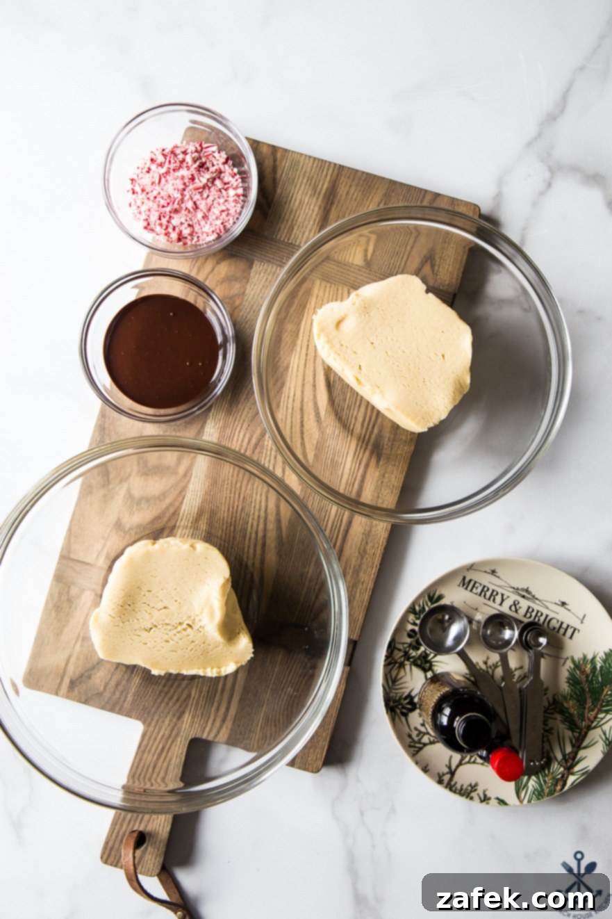 Two glass bowls containing the distinct chocolate and peppermint doughs for pinwheel cookies, resting on a rustic wooden board, ready for assembly