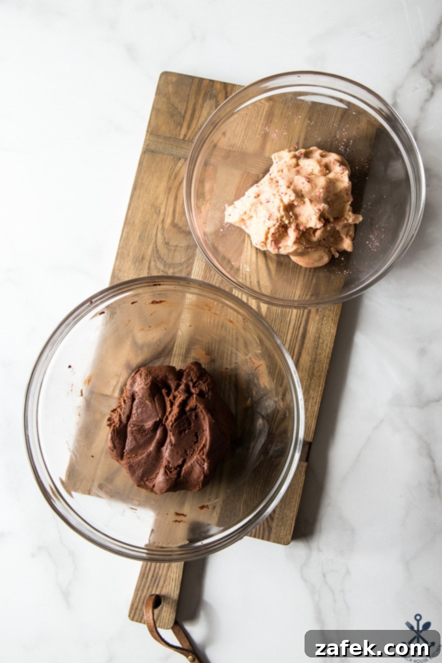 Close-up of chocolate peppermint pinwheel cookie dough in separate glass bowls on a wooden board, showcasing the distinct layers before rolling