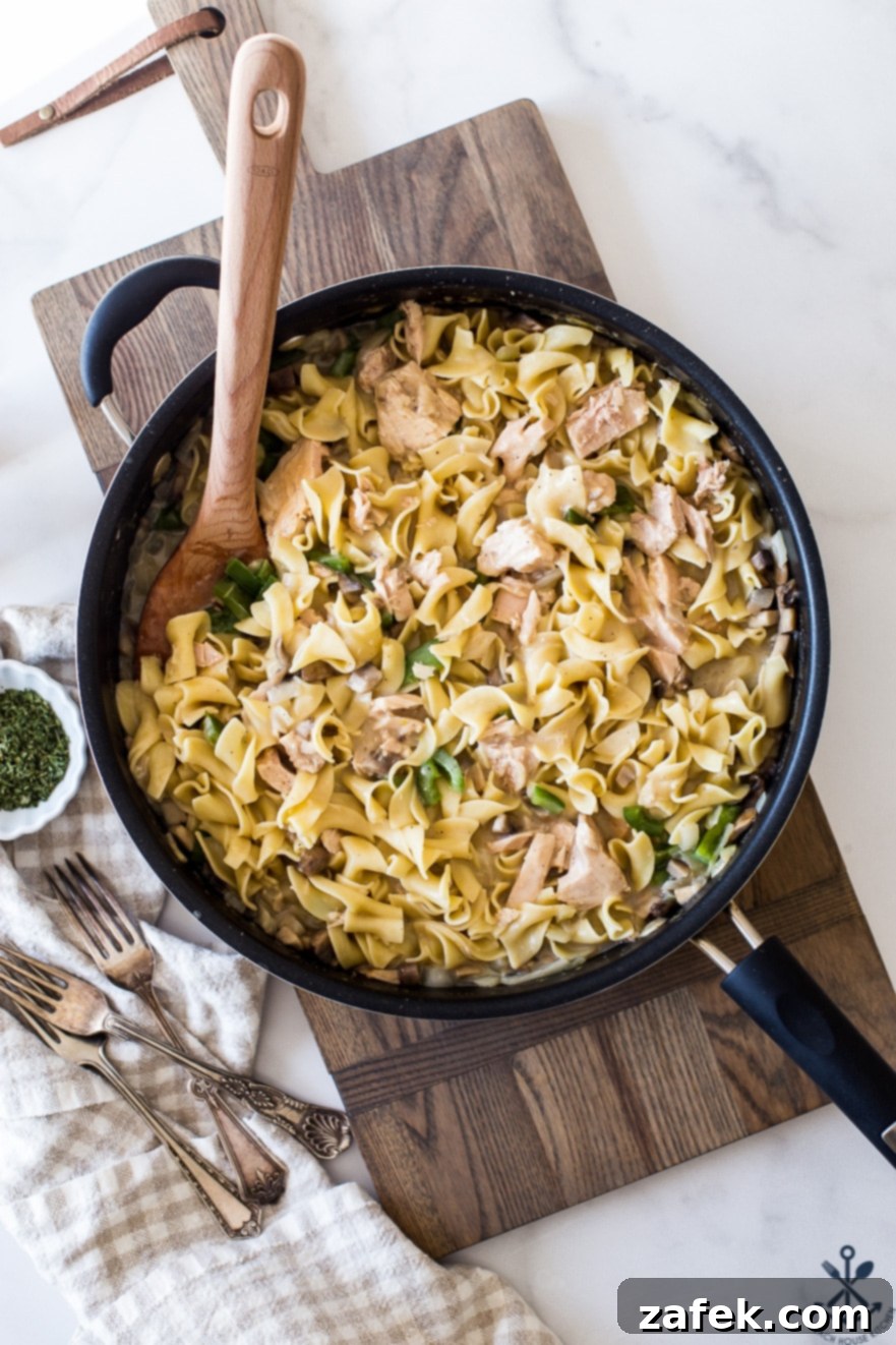 Creamy Tuna Noodle Delight 2 Overhead photo of skillet filled with golden-brown tuna noodle casserole, garnished with fresh parsley.