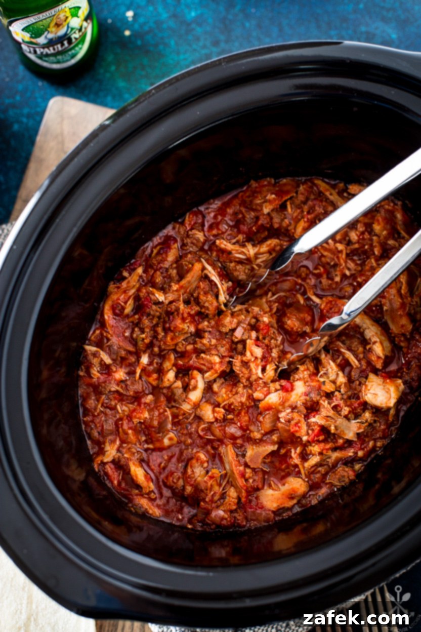 Overhead photo of a slow cooker of chicken tinga, garnished with fresh cilantro