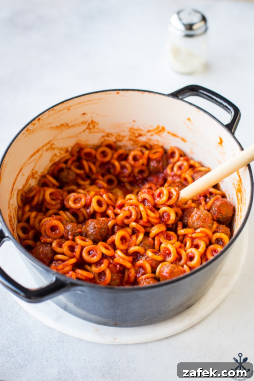 A dark pot filled with a generous serving of homemade SpaghettiO's and meatballs