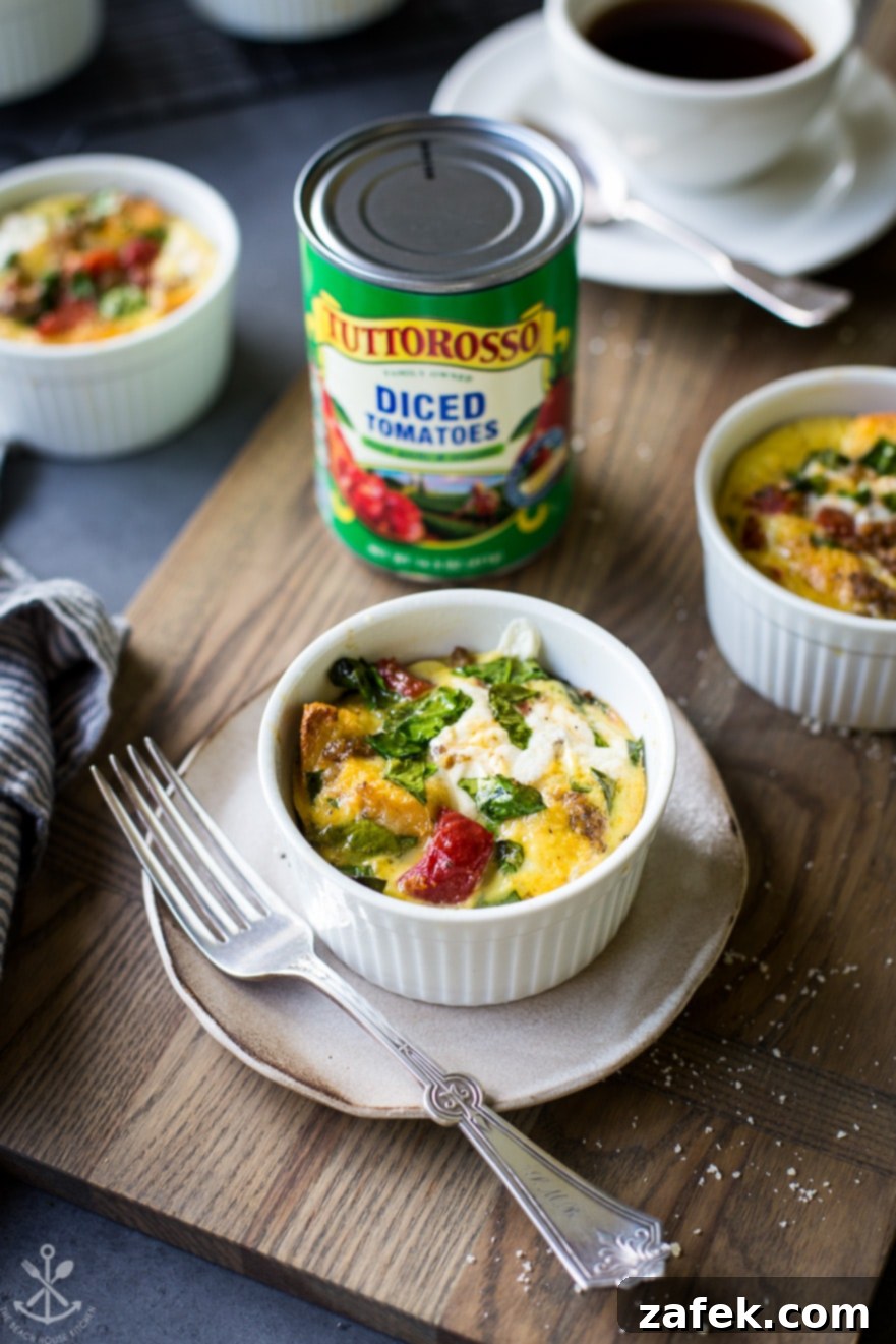 Close-up photo of a single Sausage, Tomato, Spinach, and Mozzarella Egg Cup on a small white plate with a silver fork, showcasing its appealing texture and readiness to eat