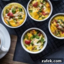 Close-up overhead photo of a single sausage, tomato, spinach, and mozzarella egg cup, showcasing the golden-brown top and savory ingredients, ideal for a meal prep recipe thumbnail