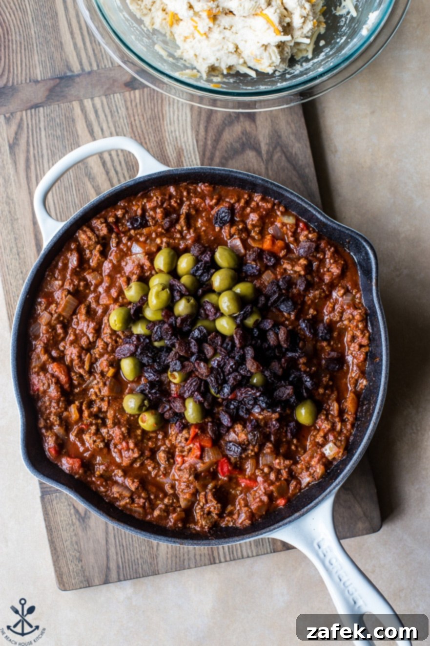Overhead photo of a rustic skillet filled to the brim with richly colored Cuban Beef Picadillo, showcasing its savory texture