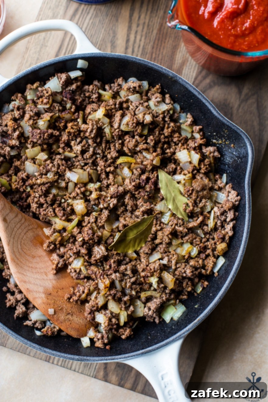 Overhead photo of finely ground beef browning in a large skillet, ready for the next steps in the picadillo recipe