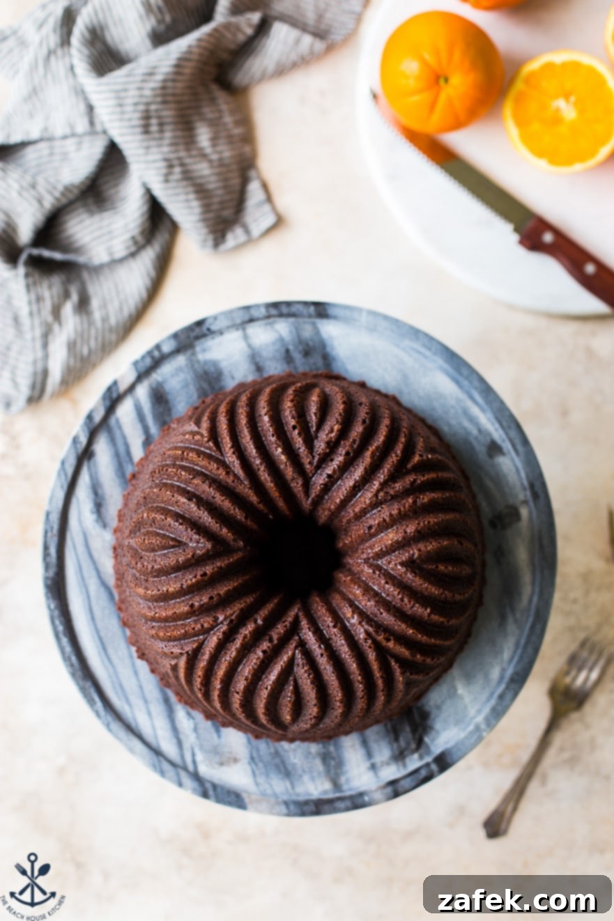 Zesty Chocolate Orange Bundt 2 Overhead photo of a chocolate orange bundt cake on a marble cake plate, elegantly presented.