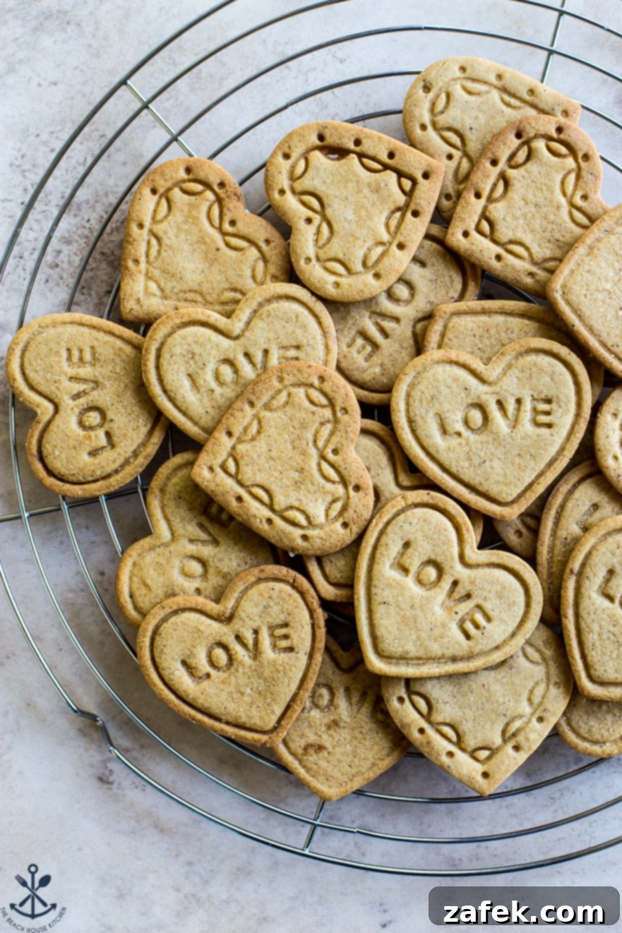 Brown Butter Honey Cardamom Delights 5 A cooling rack filled with freshly baked heart-shaped cookies, some intricately imprinted with patterns and others with the word 'LOVE', showcasing the delightful results of homemade Brown Butter Honey Cardamom Cookies.