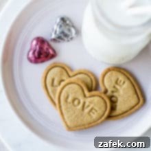 Brown Butter Honey Cardamom Delights 8 Overhead photo of 3 heart shaped cookies imprinted with LOVE on a plate with a bottle of milk