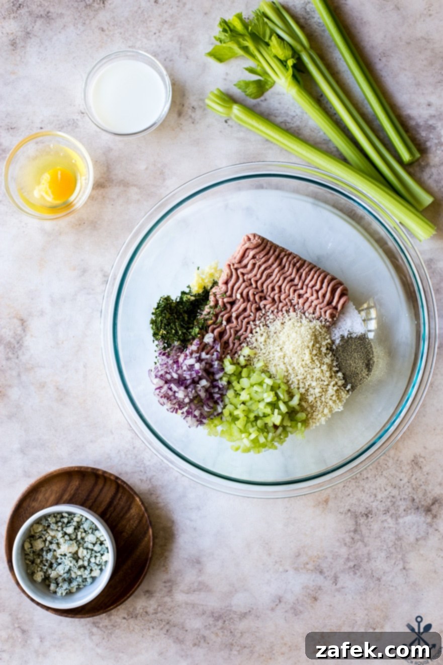 Overhead photo of ingredients for buffalo turkey meatballs, including ground turkey, panko, and chopped vegetables, in a clear glass bowl.