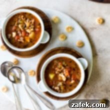Manhattan's Red Clam Chowder 7 Overhead photo of two white bowls filled with Manhattan Clam Chowder on a round marble board with three spoons.