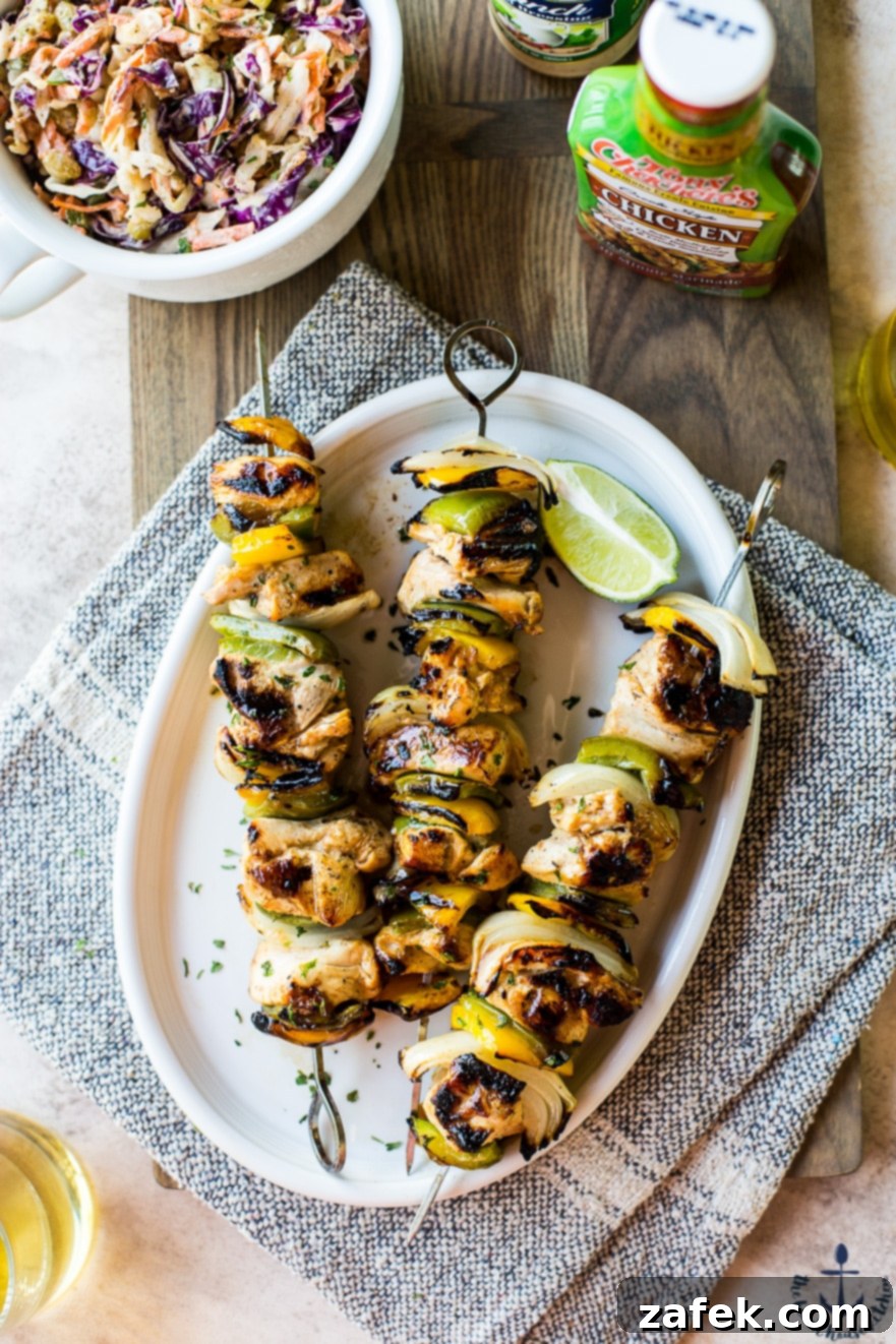 Overhead photo of chicken skewers on a white oval plate on a wooden board