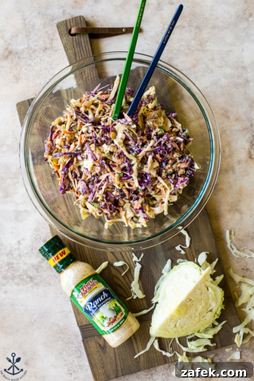Overhead photo of bacon ranch cole slaw in a glass bowl on a wooden board