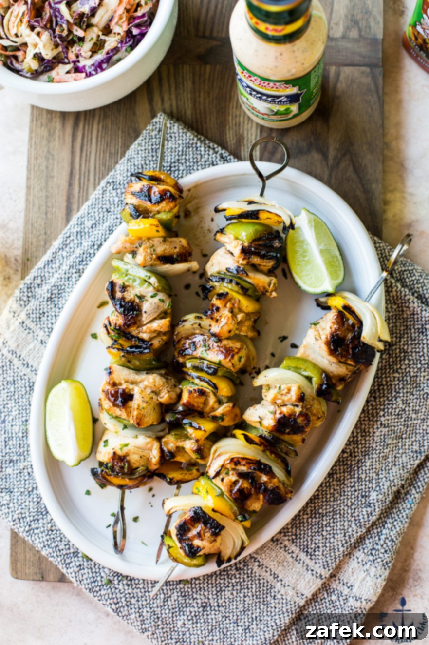 Overhead photo of cooked chicken skewers on a white oval plate on a wooden board